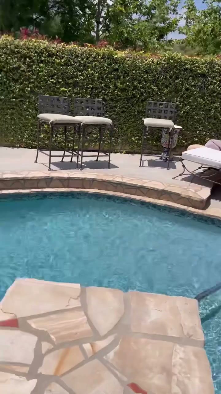 A finished stone-paved pool deck with patio furniture beside a raised spa.